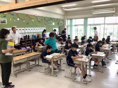 机間巡視する担任と後ろで見学する教員