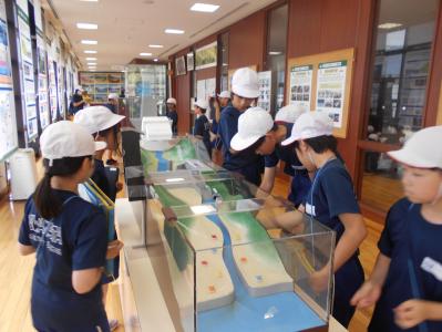 摺上川の水が流れる模型を見学する4年生