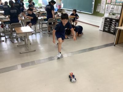 電気で自動車を走らせる児童